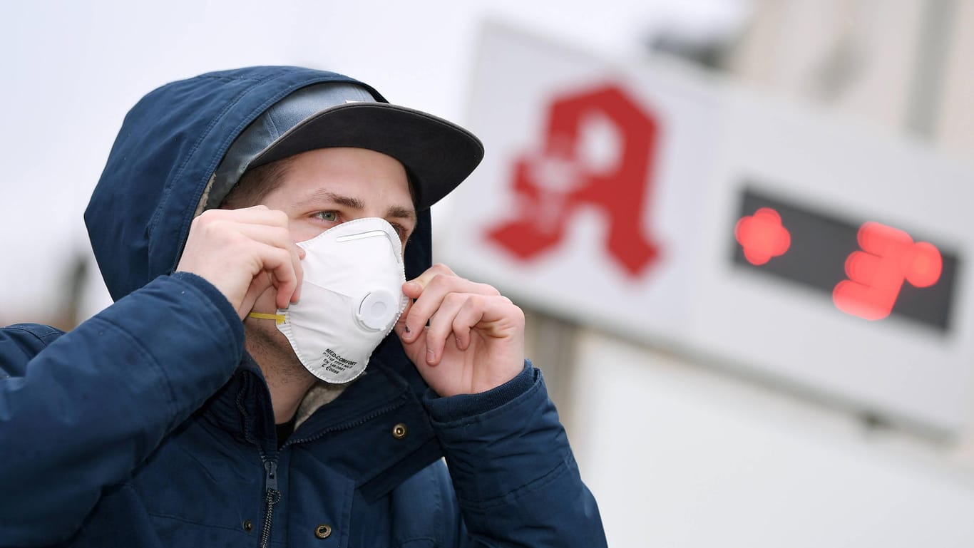 Ein Mann mit einer Schutzmaske vor einer Apotheke: Die Nachfrage nach Atemschutzmasken ist durch das Coronavirus sehr hoch.