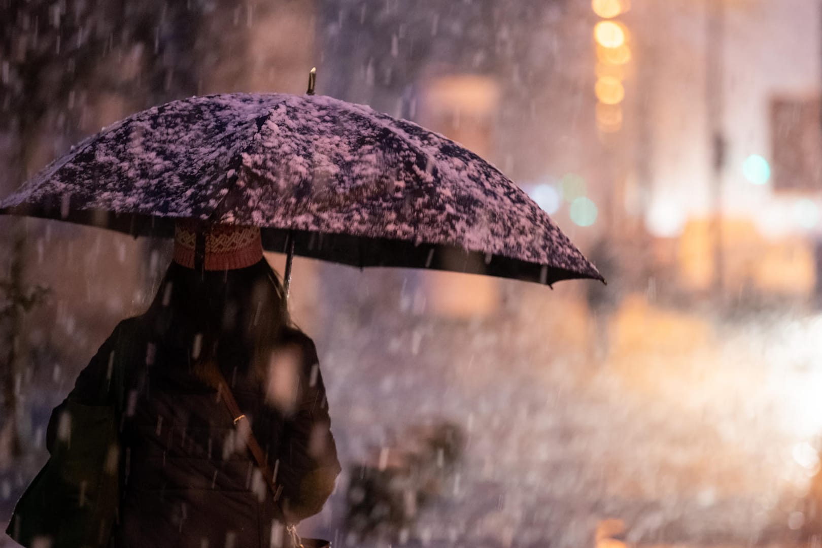 Eine Frau geht bei Schneefall auf dem Gehsteig: In Nürnberg hat es geschneit.