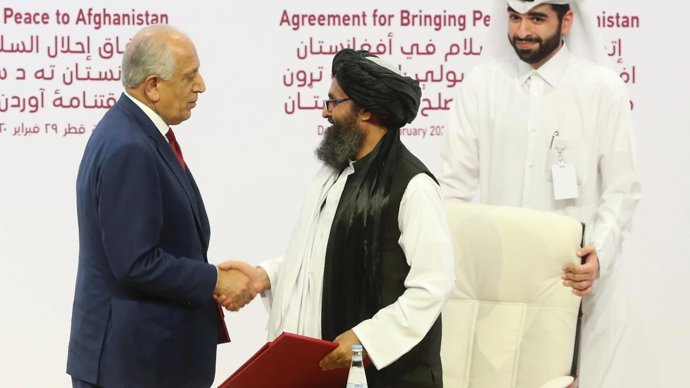 Historischer Augenblick in Doha, Katar: US-Sondergesandter Zalmay Khalilzad (l.) und Talibanführer Mullah Abdul Ghani Baradar reichen sich nach der Unterzeichnung des Abkommens die Hand.
