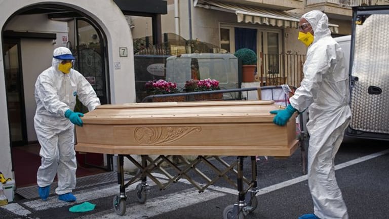 Medizinisches Personal trägt einen Sarg mit dem Leichnam einer 87-jährigen Frau aus einem Hotel im italienischen Laigueglia.