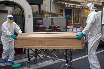 Medizinisches Personal trägt einen Sarg mit dem Leichnam einer 87-jährigen Frau aus einem Hotel im italienischen Laigueglia.