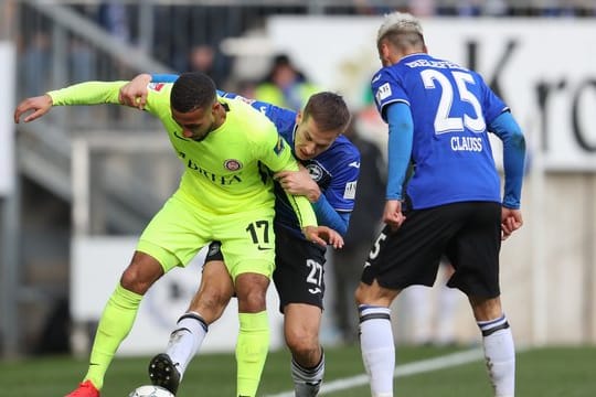 Bielefelds Cedric Brunner (M) und Jonathan Clauss (r) bedrängen im Kampf um den Ball mit Daniel-Kofi Kyereh (l) aus Wiesbaden.