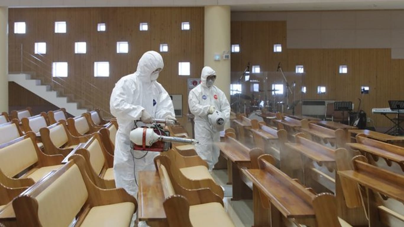 Zwei Arbeiter in Schutzkleidung versprühen Desinfektionsmittel in einer Kirche in Südkorea.