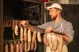 Im Fleischerhandwerk ist Nachwuchs gesucht: Der Auszubildende Maurice Münch hängt Würste zum Räuchern in den Räucherofen.