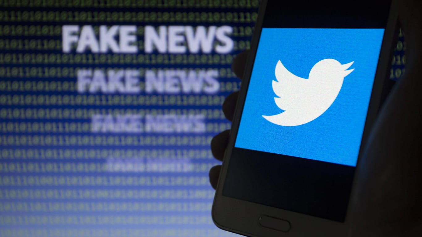 Ein Handy mit Twitter-Symbol, im Hintergrund ein "Fake News"-Schriftzug: Auf Twitter sollen sich Corona-Verschwörungstheorien verbreiten.