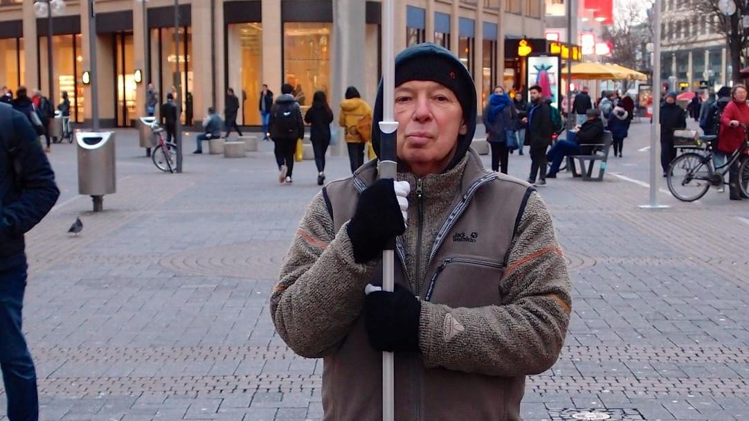 Herbert Küppers steht in der Kölner Einkaufsmeile: Mit seinem Schild will er auf bewussteren Konsum aufmerksam machen.