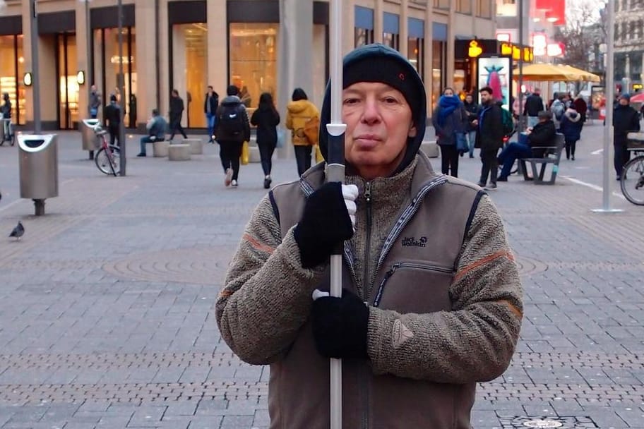 Herbert Küppers steht in der Kölner Einkaufsmeile: Mit seinem Schild will er auf bewussteren Konsum aufmerksam machen.