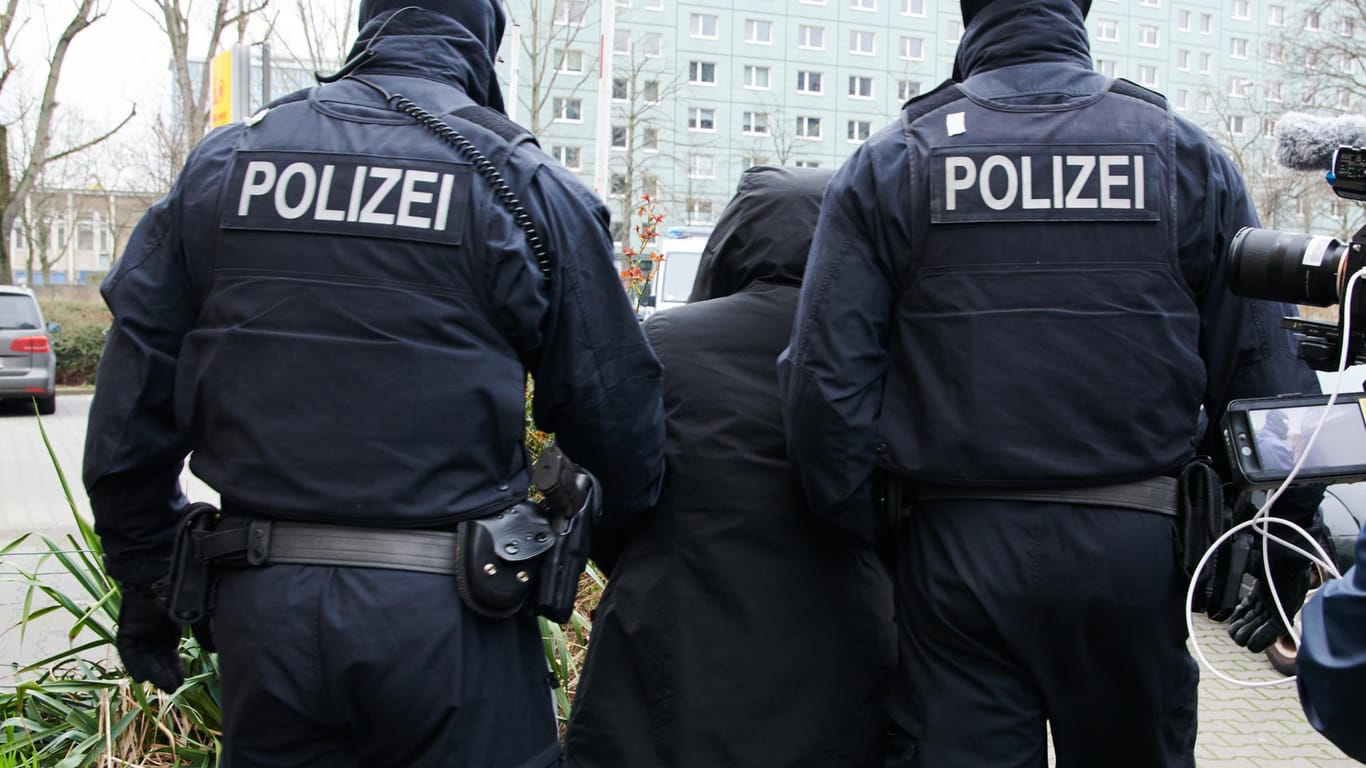 Zwei Polizisten führen in Berlin-Mitte eine Person ab: Im Rahmen einer bundesweiten Razzia gegen einen vietnamesischen Menschenhändlerring wurden auch in Berlin verschiedenen Objekte durchsucht.