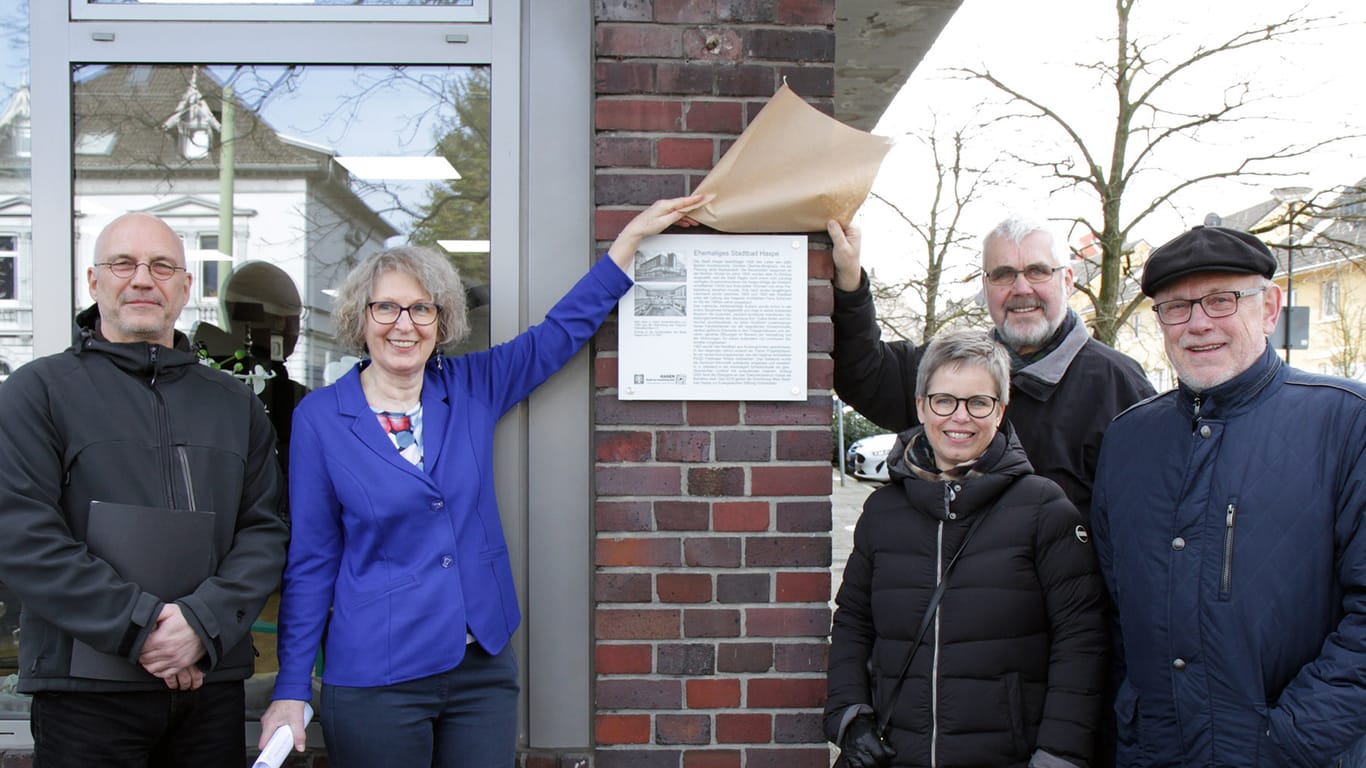 Achim Krüger (städtische Gebäudewirtschaft), Petra Kroll (Ev. Stiftung Volmarstein), Ina Hanemann (Denkmalbehörde), Jens Bergmann (Heimatbund) und Bezirksbürgermeister Dietmar Thieser enthüllen die Infotafel am Alten Stadtbad Haspe.