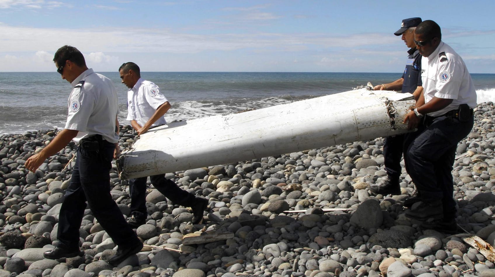 Ein Wrackteil der MH370 wurde auf La Reunion gefunden: Techniker tragen die Flügelklappe des Flugzeugs, über einen Strand bei Saint-Andre de la Reunion. (Archivfoto) Ein Wrackteil der MH370 wurde auf La Reunion gefunden: Techniker tragen die Flügelklappe des Flugzeugs, über einen Strand bei Saint-Andre de la Reunion. (Archivfoto)