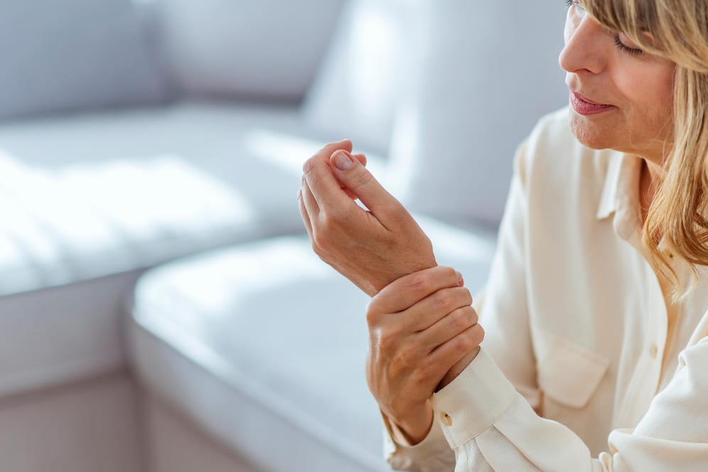 Frau mit schmerzender Hand: Im Verlauf der Wechseljahre kommt es zu Östrogenmangel. Darunter leiden auch die Knochen.