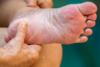 Eine Frau massiert sich den Fuß: Kribbeln im Fuß kann auf Durchblutungsstörungen hinweisen. Damit steigt das Risiko für das diabetische Fußsyndrom.