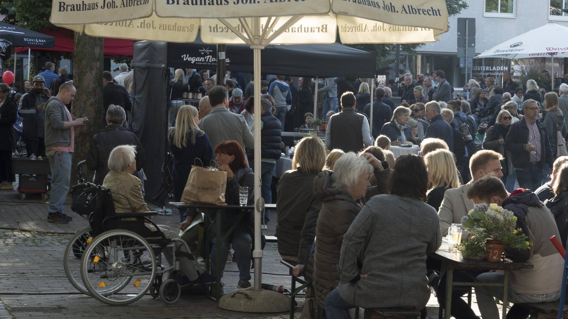 Bielefelder Abendmarkt auf dem Klosterplatz: Menschen sitzen bei Live-Musik und Getränken zusammen. Bielefelder Abendmarkt auf dem Klosterplatz: Menschen sitzen bei Live-Musik und Getränken zusammen.