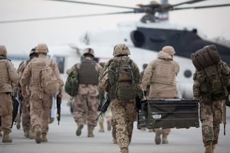 Bundeswehrsoldaten (r) auf dem Weg zu einem zivilen Hubschrauber.
