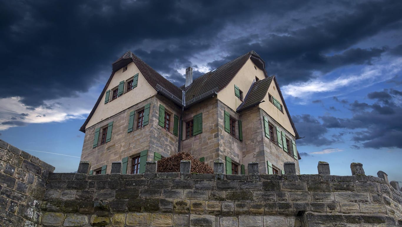 Dunke Wolken über einem Schloss in Franken: Das Wetter der kommenden Tage wird ungemütlich.