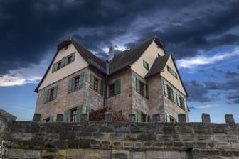 Dunke Wolken über einem Schloss in Franken: Das Wetter der kommenden Tage wird ungemütlich.