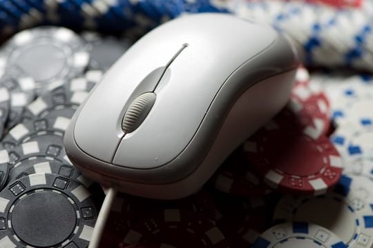 Eine Computermaus liegt auf einem Stapel Glücksspiel-Jetons.