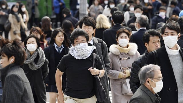 Wegen des Coronavirus tragen viele Passanten in Tokio Mundschutz. Wegen des Coronavirus tragen viele Passanten in Tokio Mundschutz.