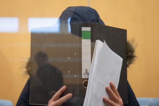 Die Angeklagte verbirgt im Düsseldorfer Oberlandesgericht ihr Gesicht hinter einem Aktenordner.