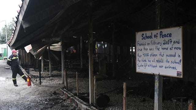 Ein Feuerwehrmann steht vor dem ausgebrannten Gemeinschaftszentrum "One Happy Family" auf Lesbos. Ein Feuerwehrmann steht vor dem ausgebrannten Gemeinschaftszentrum "One Happy Family" auf Lesbos.