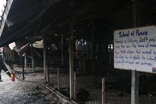 Ein Feuerwehrmann steht vor dem ausgebrannten Gemeinschaftszentrum "One Happy Family" auf Lesbos.