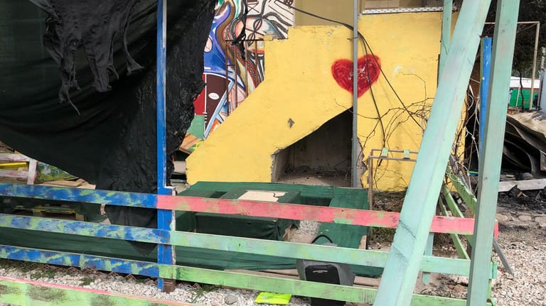 Ein bunter Zaun und Wandmalereien im Tageszentrum "One Happy Family" haben das Feuer überlebt. Der Bereich, in dem unterrichtet wurde, ist komplett zerstört.