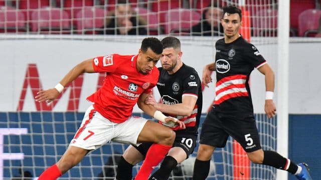 Der Mainzer Robin Quaison (l) versucht sich gegen die Düsseldorfer Valon Berisha und Kaan Ayhan durchzusetzen. Der Mainzer Robin Quaison (l) versucht sich gegen die Düsseldorfer Valon Berisha und Kaan Ayhan durchzusetzen.