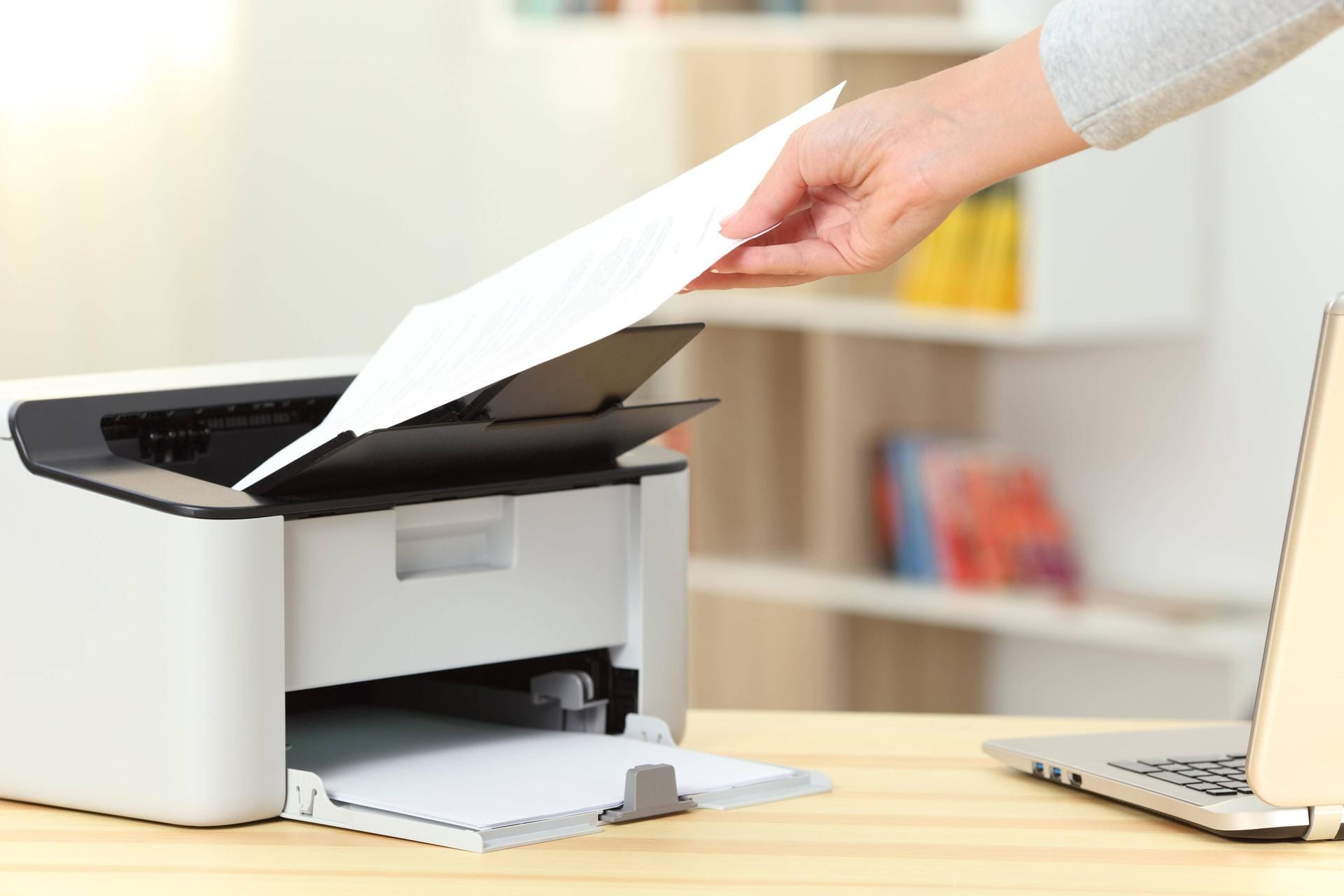 Eine Frau nimmt ein Blatt aus einem Drucker: Nach Windows-Updates kann es zu Druckerproblemen kommen.