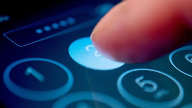 Jemand tippt einen Code in ein Smartphone: Ein vierstelliger Code kann als Schutz genügen, die Zahlen sollten aber vernünftig gewählt werden.