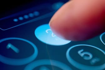Jemand tippt einen Code in ein Smartphone: Ein vierstelliger Code kann als Schutz genügen, die Zahlen sollten aber vernünftig gewählt werden.