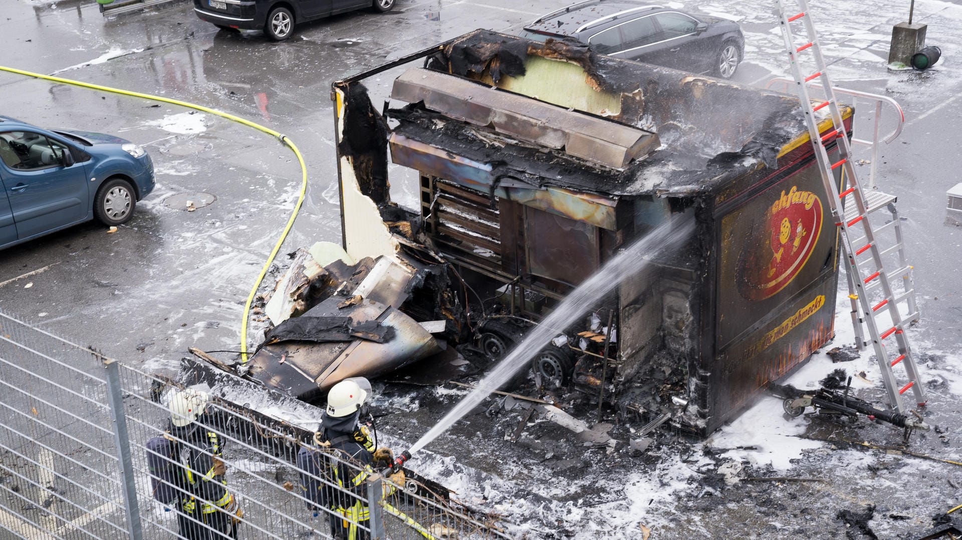 Feuerwehr-Leute löschen einen Imbisswagen: Er ist plötzlich vor einem Realmarkt in Bielefeld explodiert. Feuerwehr-Leute löschen einen Imbisswagen: Er ist plötzlich vor einem Realmarkt in Bielefeld explodiert.