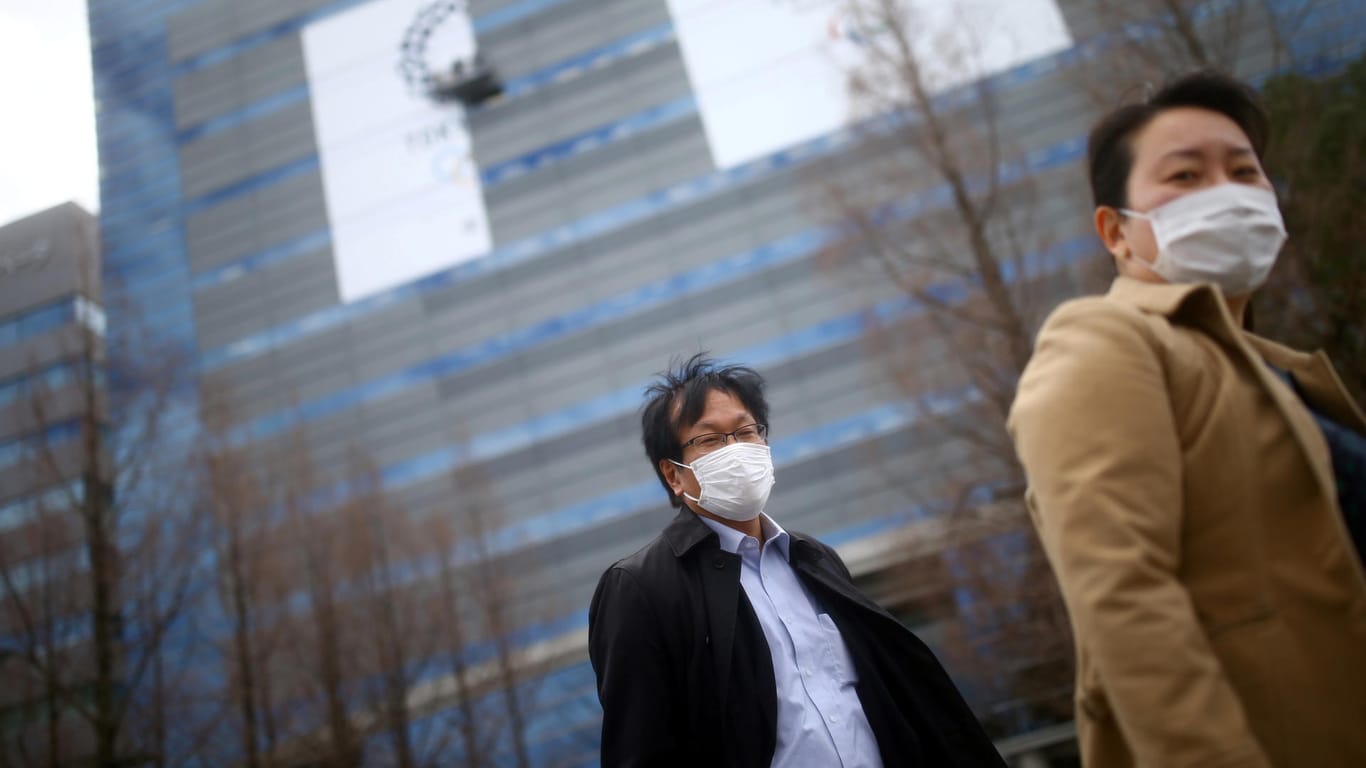In Tokio schützen sich Menschen mit einer Atemmaske: Kritiker werfen der Regierung vor, nicht ausreichend zu testen – wohl, um die Zahl bekannter Infektionsfälle niedrig zu halten.