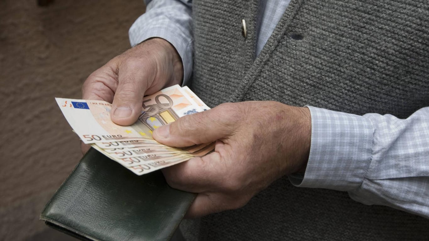 Ein älterer Mann hält Bargeld in der Hand: Senioren müssen bei anonymen Anrufen besonders wachsam sein.