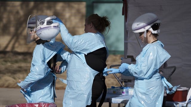 Im Kampf gegen die Lungenkrankheit: Gesundheitsmitarbeiter ziehen ihre Schutzkleidung an, bevor Menschen auf das neue Coronavirus getestet werden. Im Kampf gegen die Lungenkrankheit: Gesundheitsmitarbeiter ziehen ihre Schutzkleidung an, bevor Menschen auf das neue Coronavirus getestet werden.