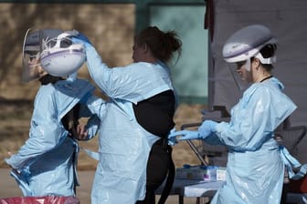 Im Kampf gegen die Lungenkrankheit: Gesundheitsmitarbeiter ziehen ihre Schutzkleidung an, bevor Menschen auf das neue Coronavirus getestet werden.
