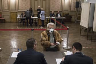 Eine Wählerin mit Atemschutzmaske registriert sich in einem Wahllokal in der französisch-italienischen Grenzstadt Menton.