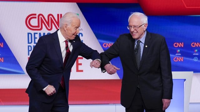 Bernie Sanders (r), und Joe Biden begrüßen sich mit ihren Ellenbogen. Bernie Sanders (r), und Joe Biden begrüßen sich mit ihren Ellenbogen.