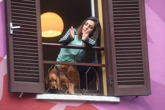 Sperrzone in Italien: Eine Frau applaudiert am Fenster ihrer Wohnung in der Innenstadt von Mailand vorbeifahrenden Einsatzfahrzeugen, Ärzten und Sanitätern.