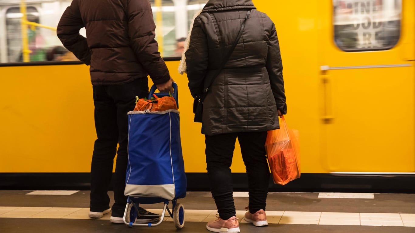 Menschen mit vollen Einkaufstrolley warten auf die U-Bahn: Nachbarn bieten Hilfe bei Besorgungen.