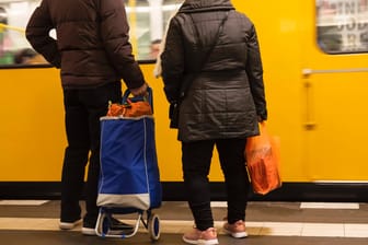 Menschen mit vollen Einkaufstrolley warten auf die U-Bahn: Nachbarn bieten Hilfe bei Besorgungen.