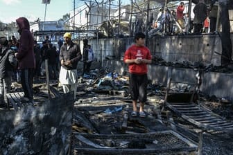 Flüchtlinge stehen im Lager Moria auf den abgebrannten Überresten eines Containerhauses.