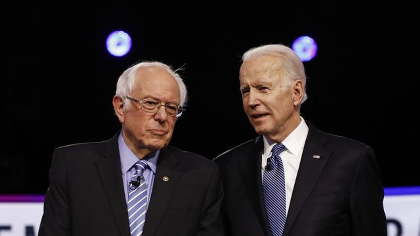 Bernie Sanders (l) und Joe Biden stehen im Februar während einer TV-Debatte nebeneinander.