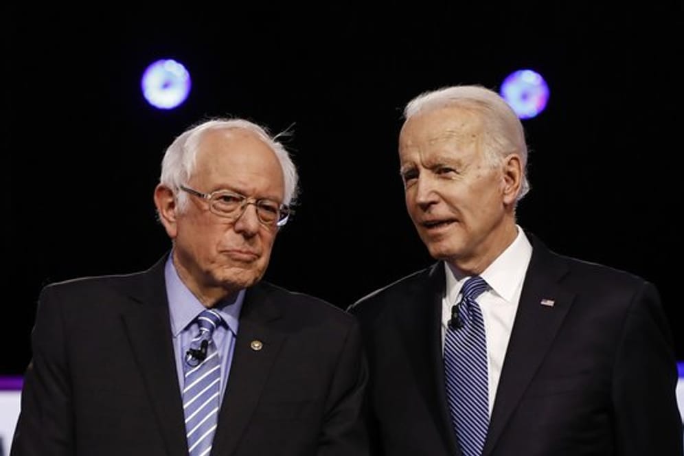 Bernie Sanders (l) und Joe Biden stehen im Februar während einer TV-Debatte nebeneinander.