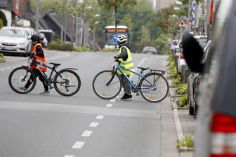 Kinder überqueren mit einem Fahrrad die Straße: In Hagen konnte ein Mann zwei Kinder vor einem Unfall retten (Symbolbild).