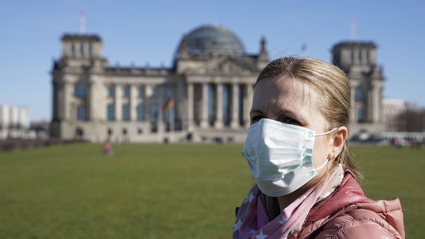 Frau mit Mundschutz vor dem Bundestag