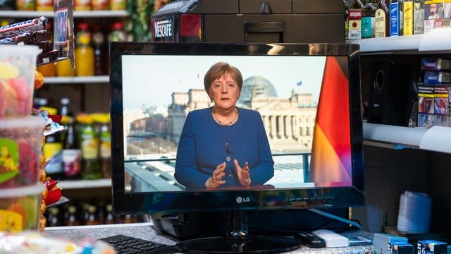 In einem Spätkauf läuft die TV-Ansprache von Bundeskanzlerin Merkel auf einem kleinen Fernseher. In einem Spätkauf läuft die TV-Ansprache von Bundeskanzlerin Merkel auf einem kleinen Fernseher.