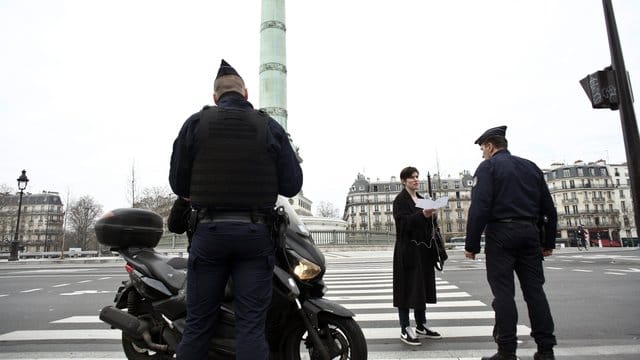 Polizeibeamte kontrollieren die Ausgangsformulare an einer Kontrollstelle in Paris. Polizeibeamte kontrollieren die Ausgangsformulare an einer Kontrollstelle in Paris.