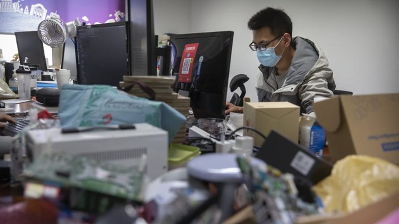 Ein Mann trägt bei der Arbeit in einem Technologieunternehmen in Peking einen Mundschutz.