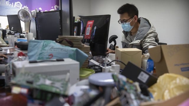 Ein Mann trägt bei der Arbeit in einem Technologieunternehmen in Peking einen Mundschutz. Ein Mann trägt bei der Arbeit in einem Technologieunternehmen in Peking einen Mundschutz.