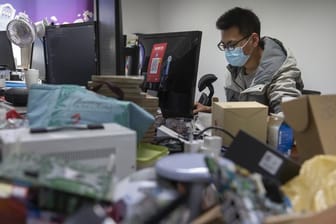 Ein Mann trägt bei der Arbeit in einem Technologieunternehmen in Peking einen Mundschutz.